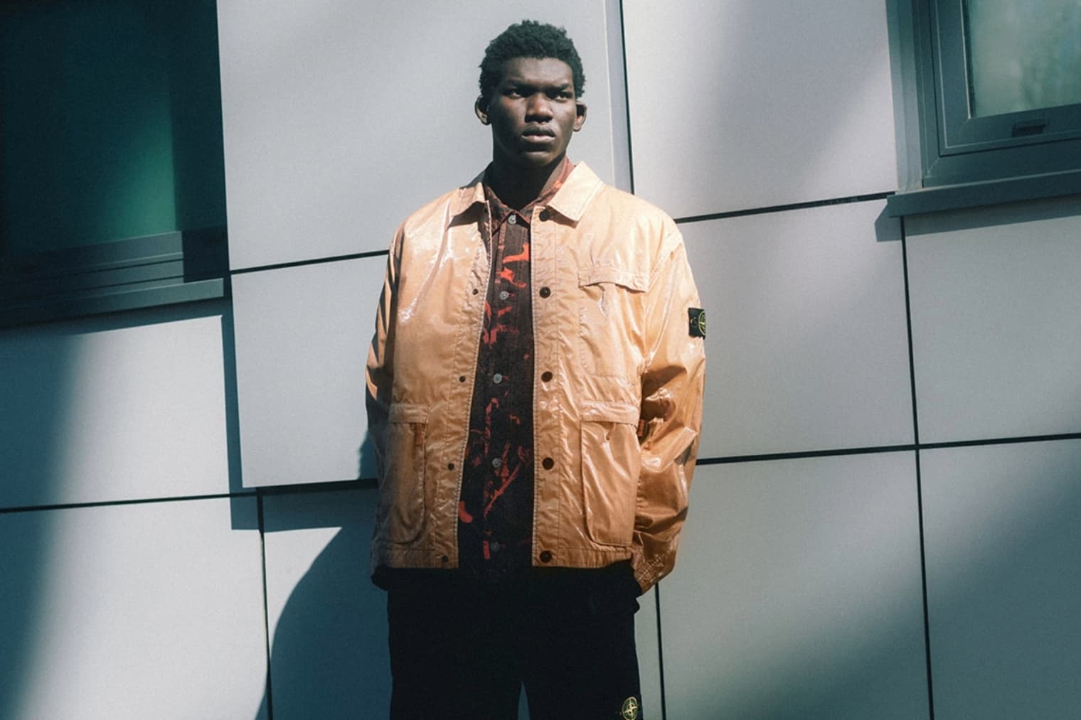 A model wears a nylon Stone Island overshirt in orange 
