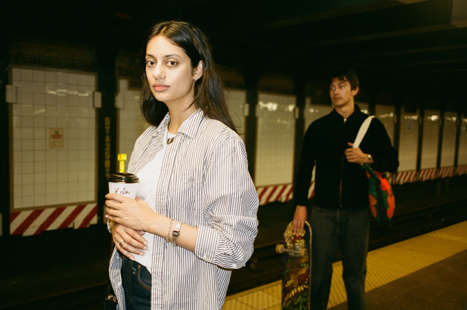 A woman and a man standing on the platform of a subway station. 