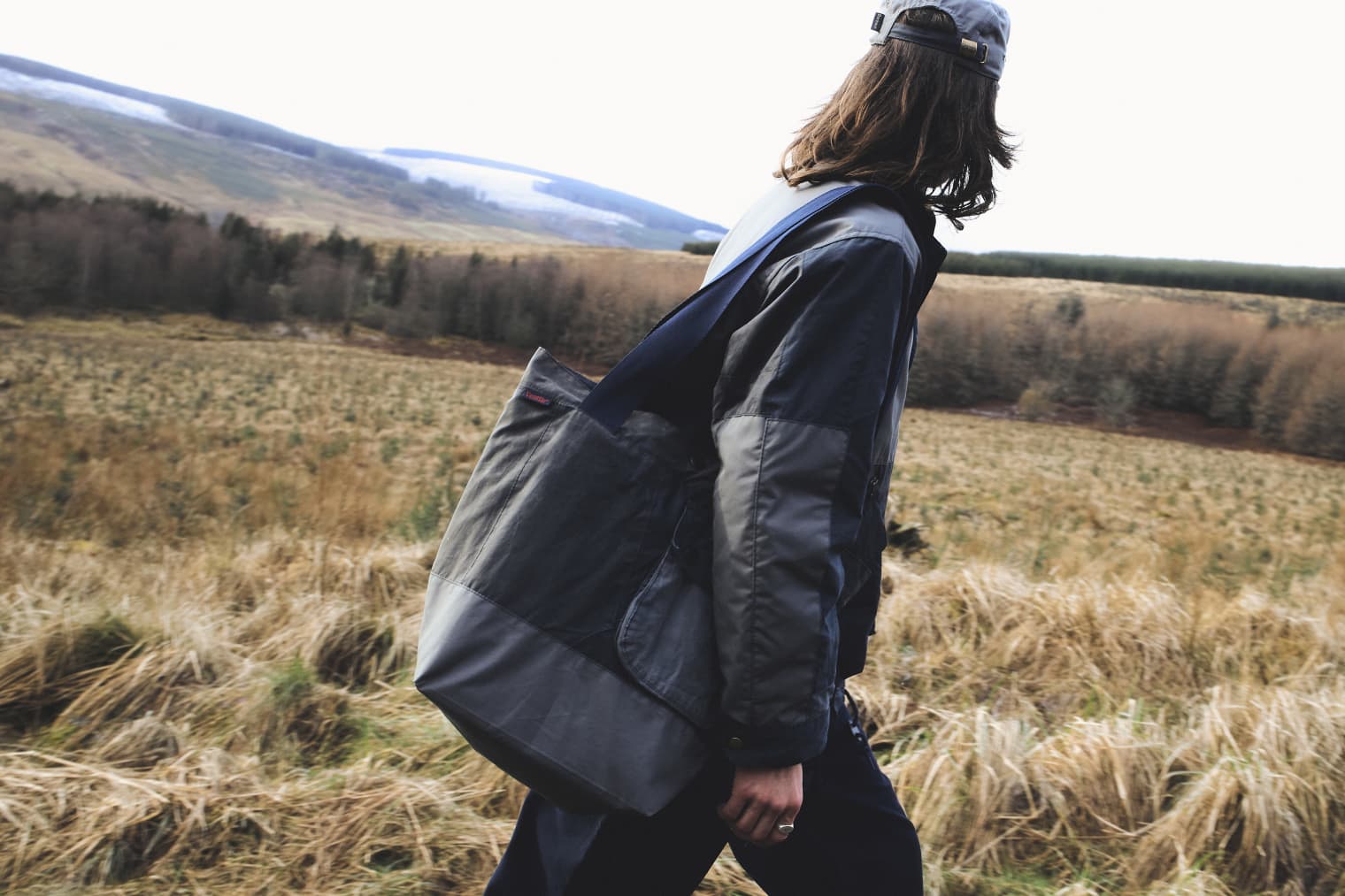 A man walking in the countryside wearing a Barbour jacket. 