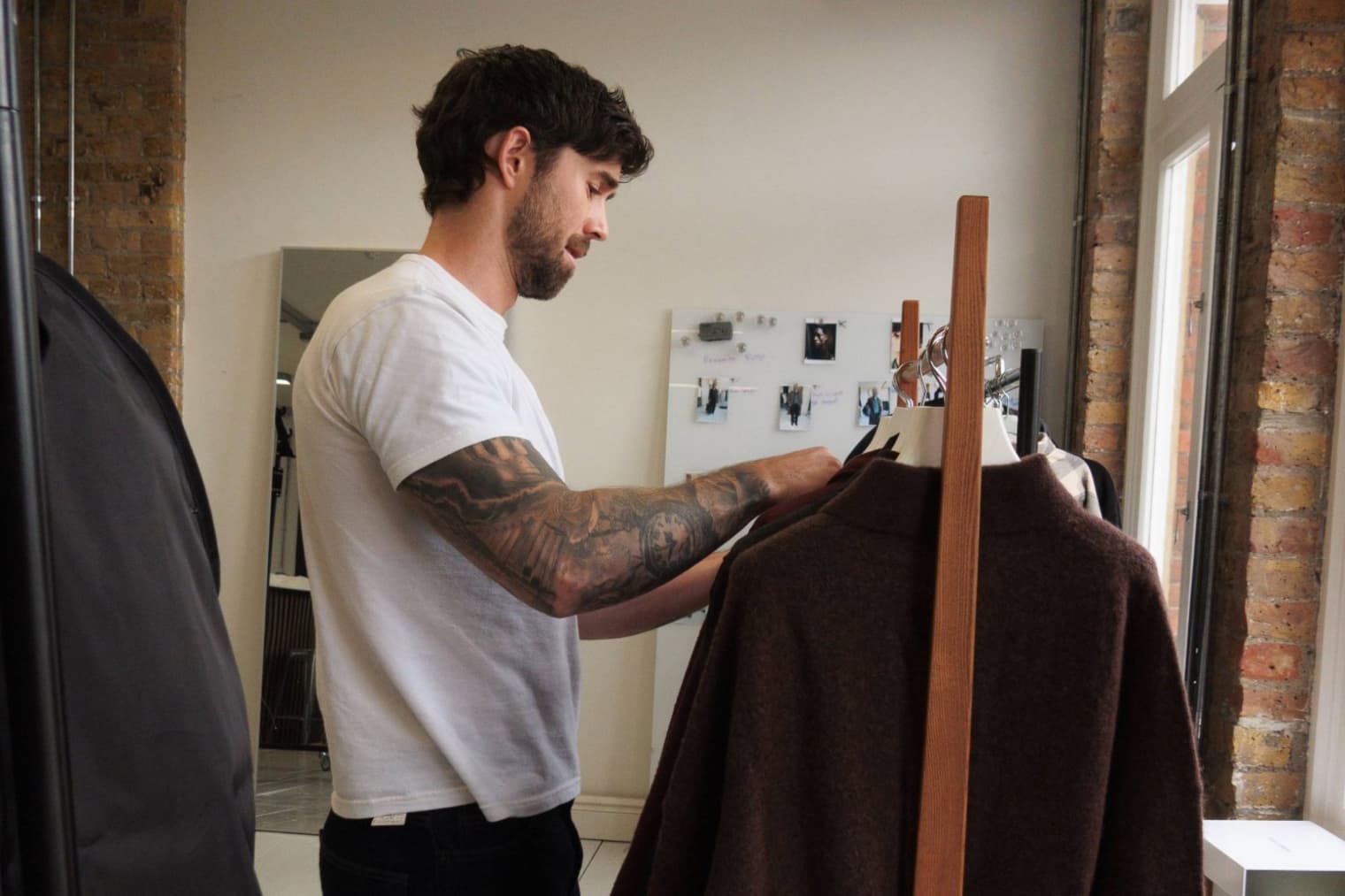 Daniel Simmons looks through a rail of clothes in his studio