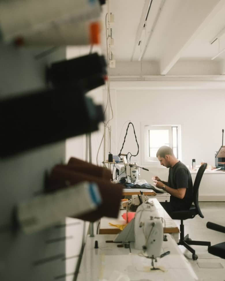 A man sits at a sewing machine in a clothing workshop