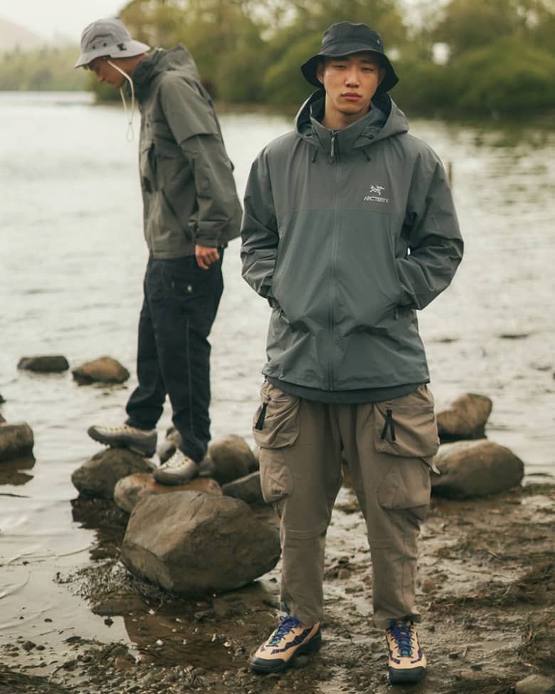 Two models wear Arc'teryx jackets at a river