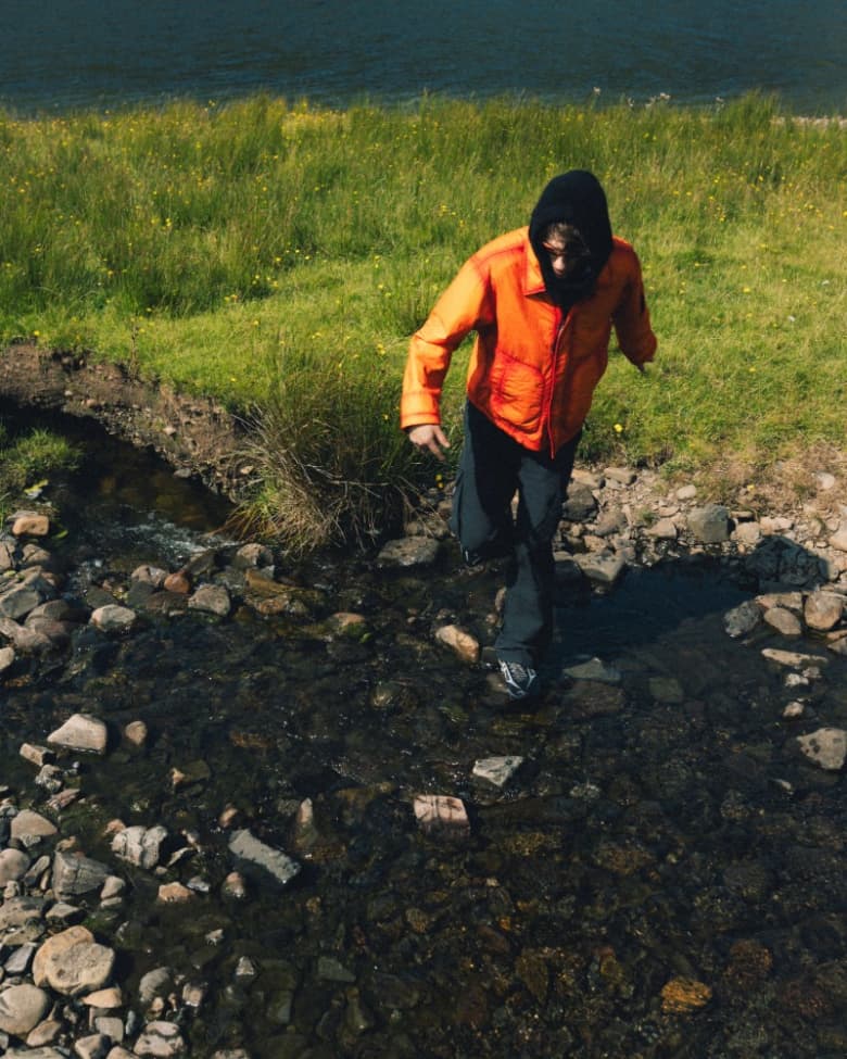 A model wearing a transitional jacket in orange