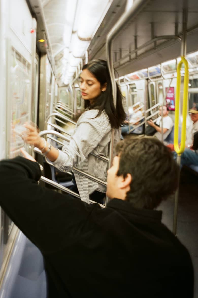 A man and a woman looking out of the window on a subway train. 