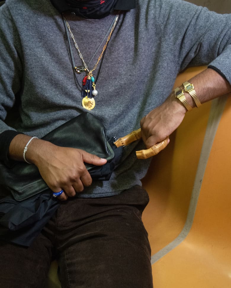 A man wearing a Timex watch on his wrist taking an umbrella out of a bag.