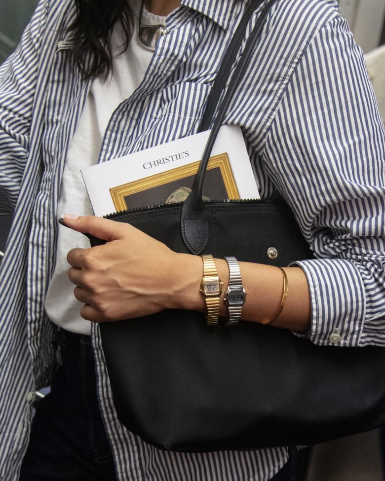 A woman wearing a Timex watch on her wrist holds her handbag.