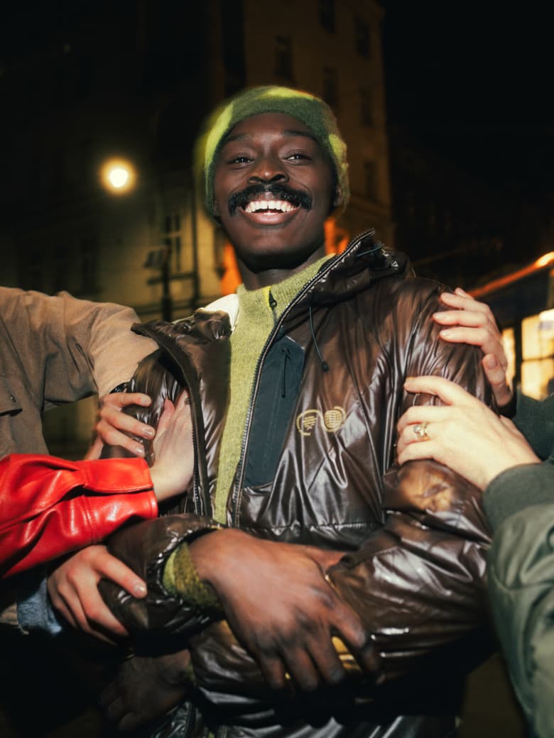 A man wearing Purple Mountain Observatory coat, with hands touching it to show the heat colour changing technology.