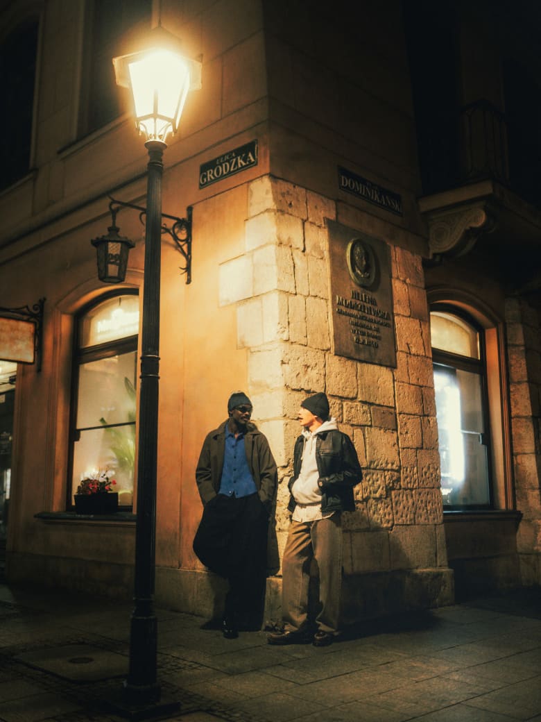 Two man standing wearing Champion Hoodie, M K I shirt, Levi Jeans and Acne studios beanie. 