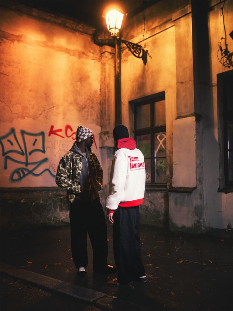 Two men wearing Carhartt WIP jacket, Our Legacy hoodie, END. x Puma sneakers and Le Specs sunglasses.