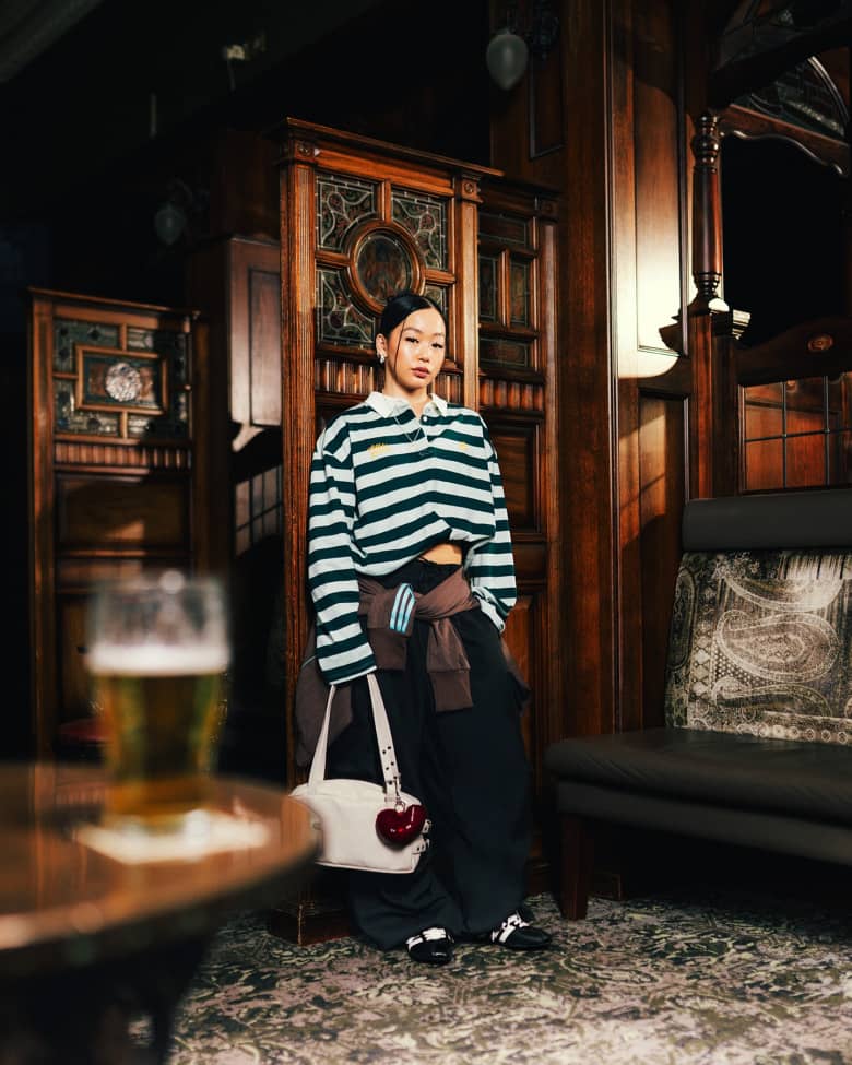 A woman wearing the end Adidas Tokyo black and white sneaker, in a pub.