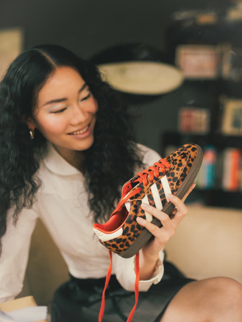 A woman holding a leopard print adidas Samba OG W sneaker