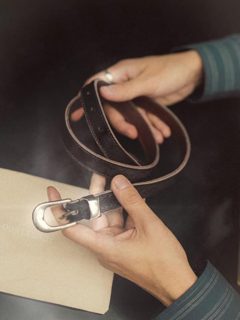 Man holding Our Legacy 2cm Belt in the colours  Chocolate Hair On Hide.