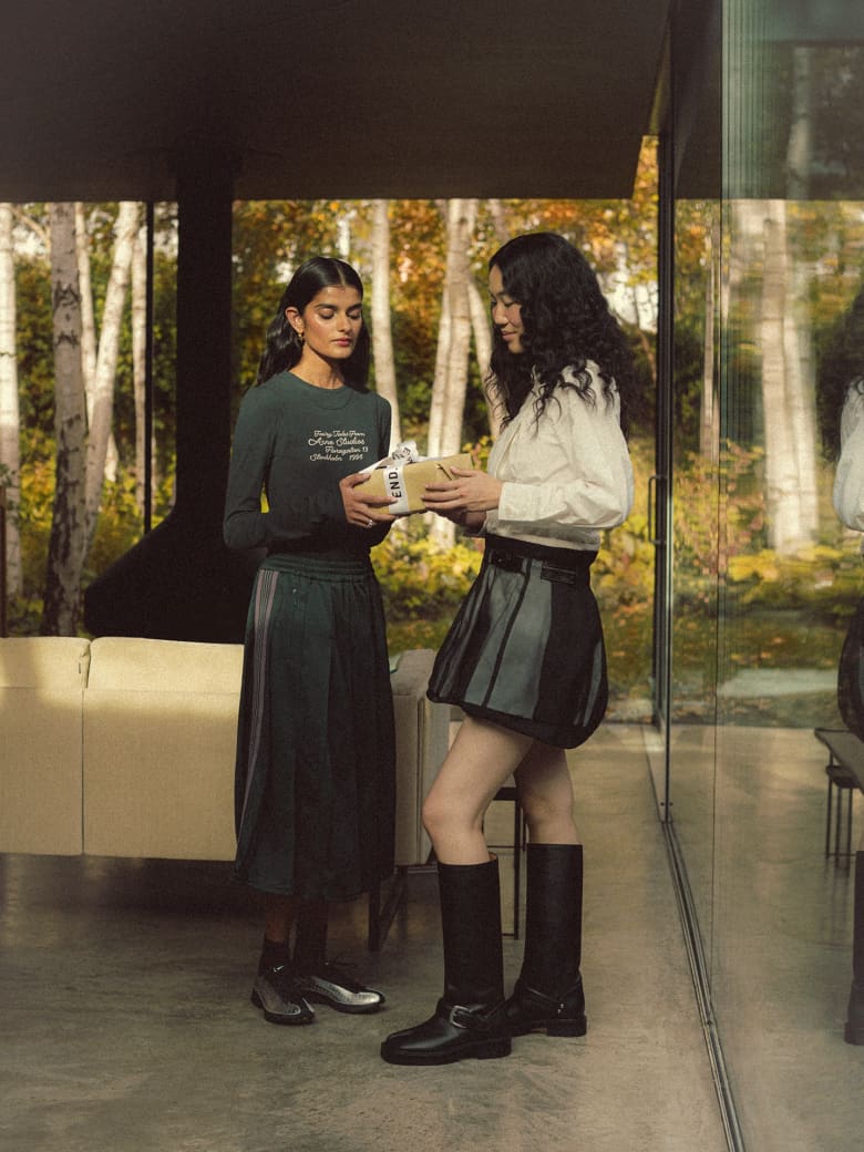 Two women exchanging a gift wearing an Acne Studios T-shirt and Maison Margiela Boots