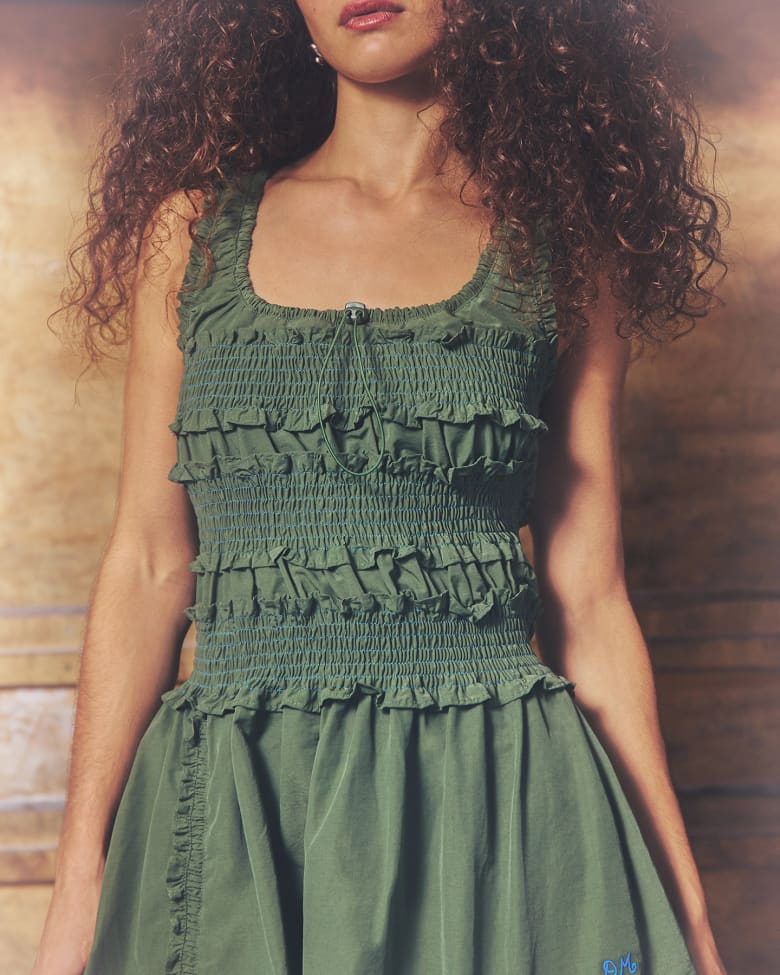 A close up of a woman wearing a green Damson Madder Presented by END. dress
