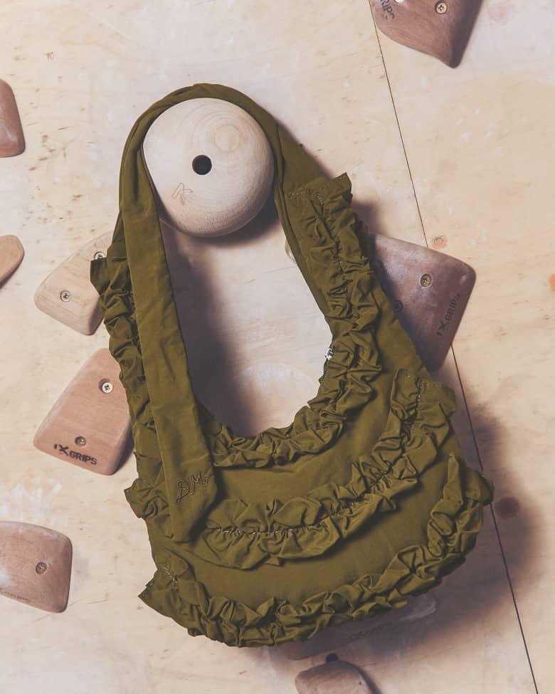 A green handbag hung on a climbing wall. 