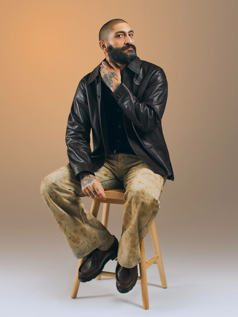 A man sitting down wearing a black leather jacket. 