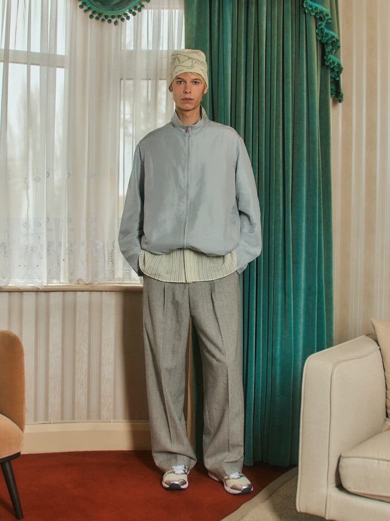 A man standing by a window in a mid-century living room. 