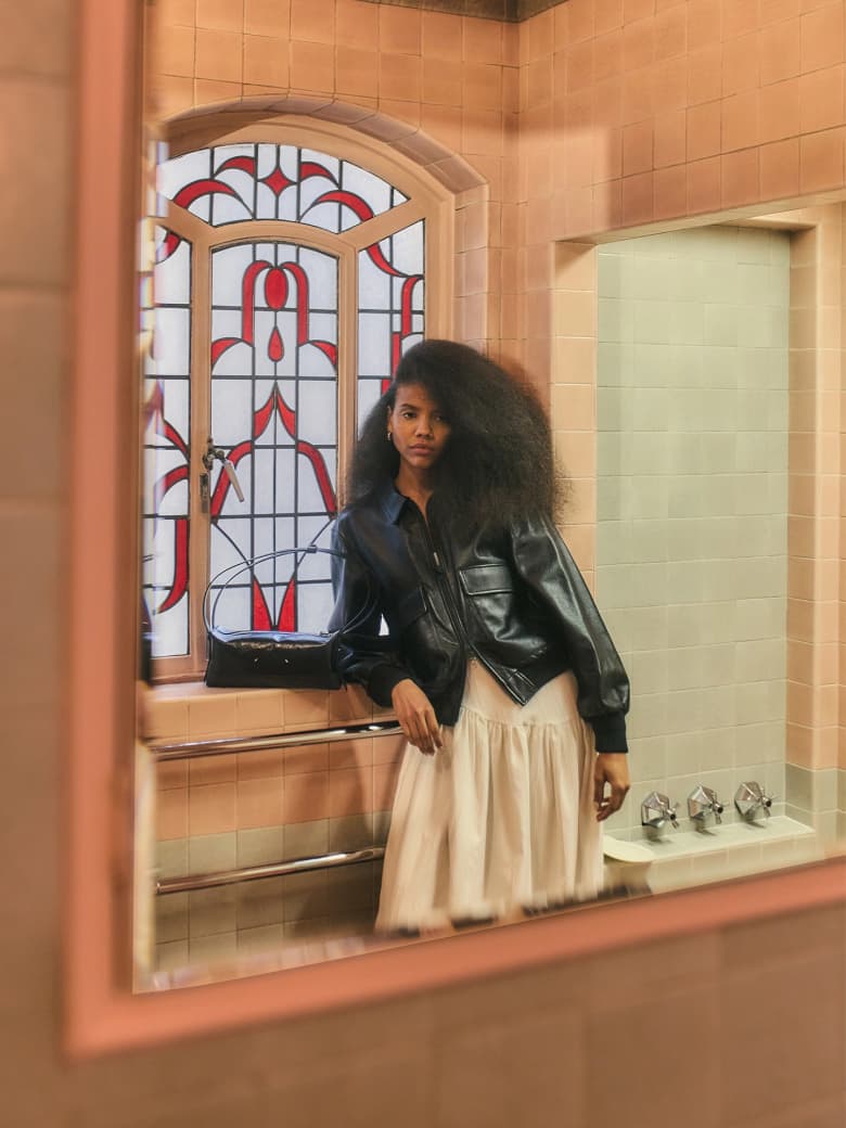 The reflection of a woman in a bathroom mirror. 