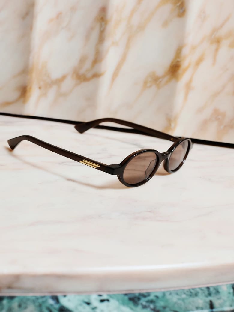 A pair of sunglasses placed on a white side table. 