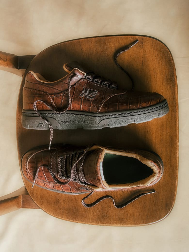 A pair of brown leather trainers placed on a wooden stool. 