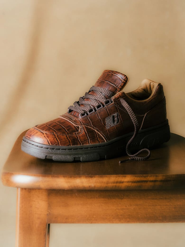 A brown leather trainer placed on a wooden stool. 