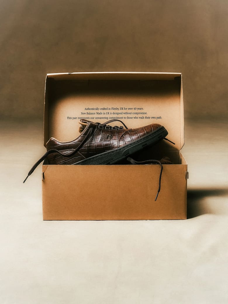 A brown leather trainer in a cardboard shoebox. 