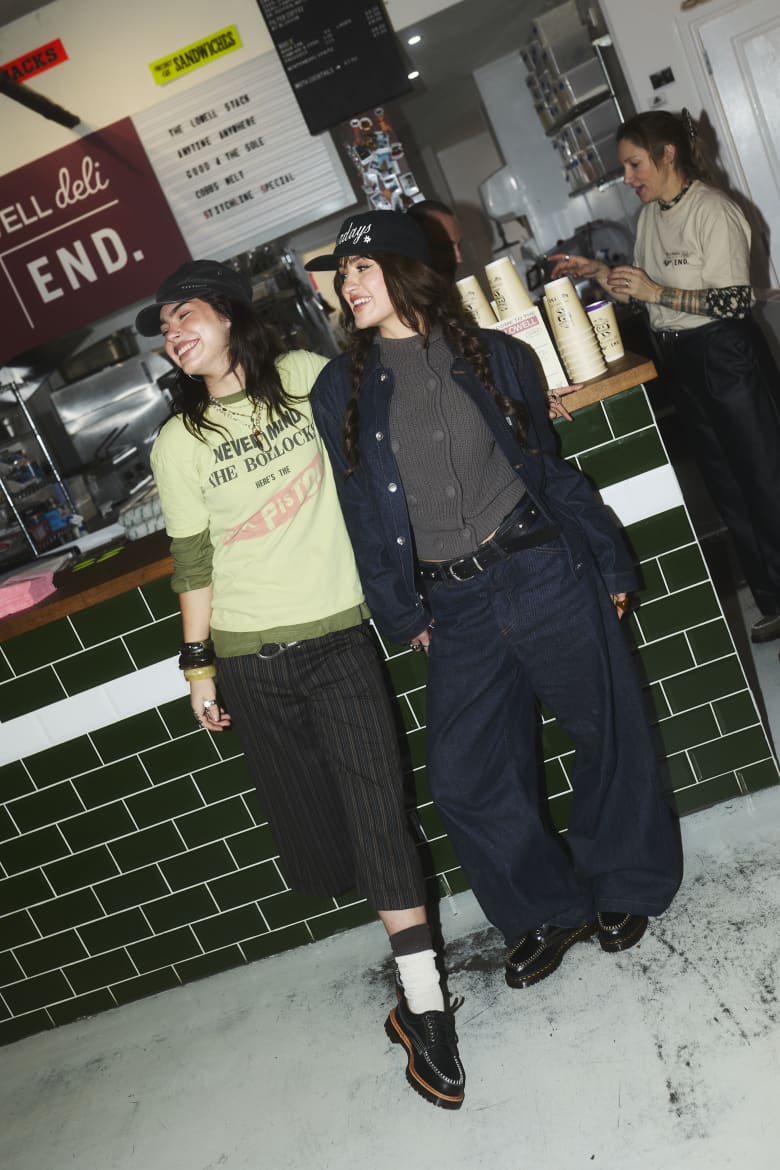Two women standing by the counter in a shop looking to the left. 