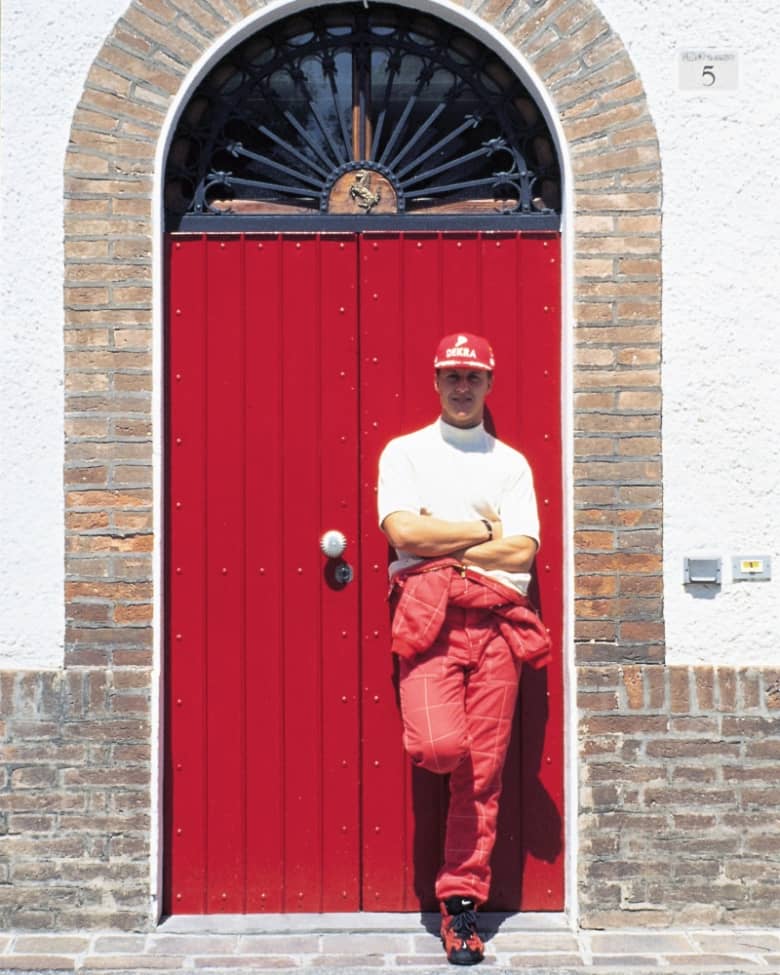 Michael Schumacher poses in front of a red door