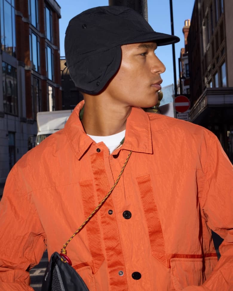 A model wears a Stone Island jacket in orange